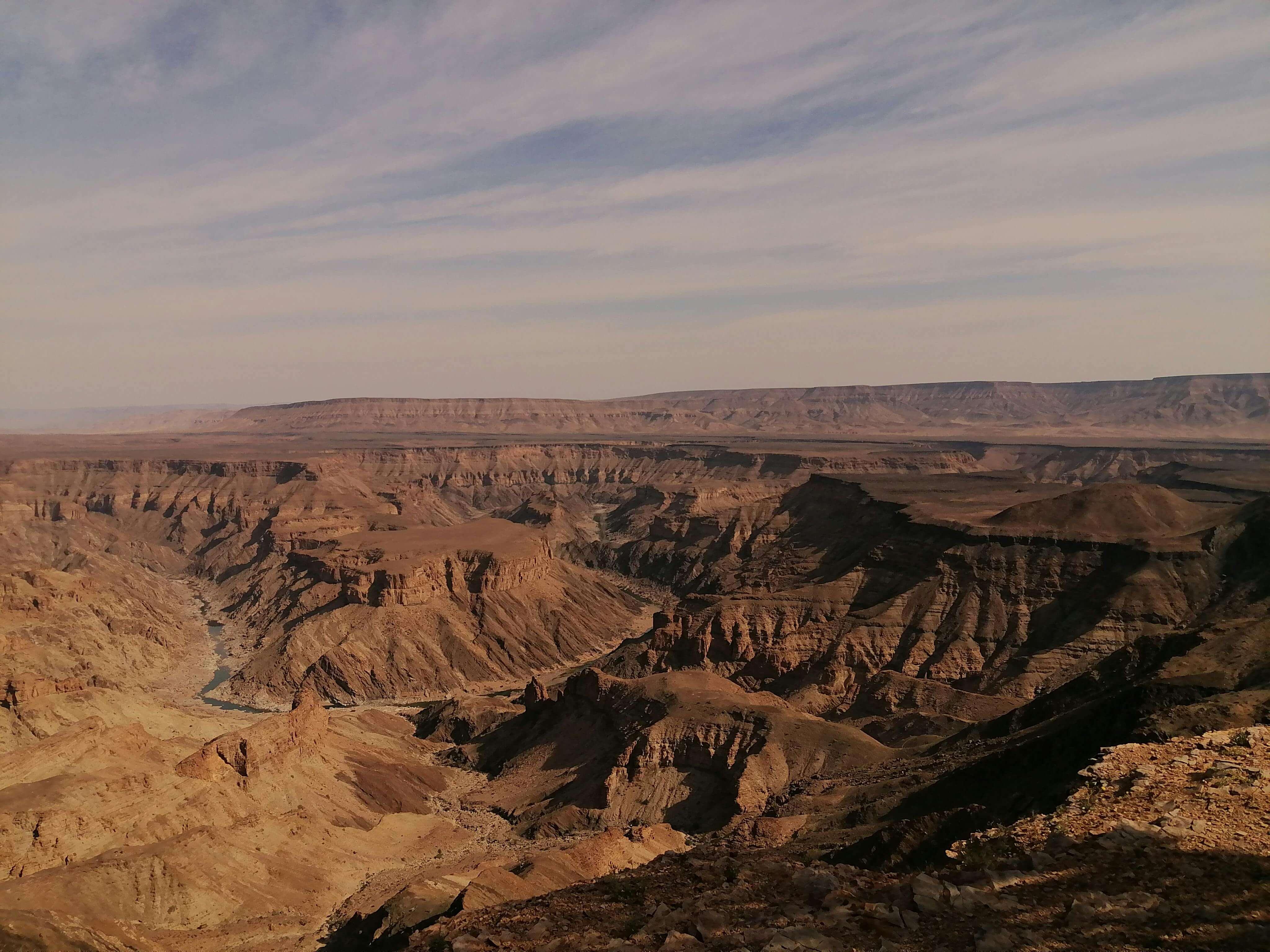 Stunning aerial view of a vast desert canyon with layered rock formations under a clear sky