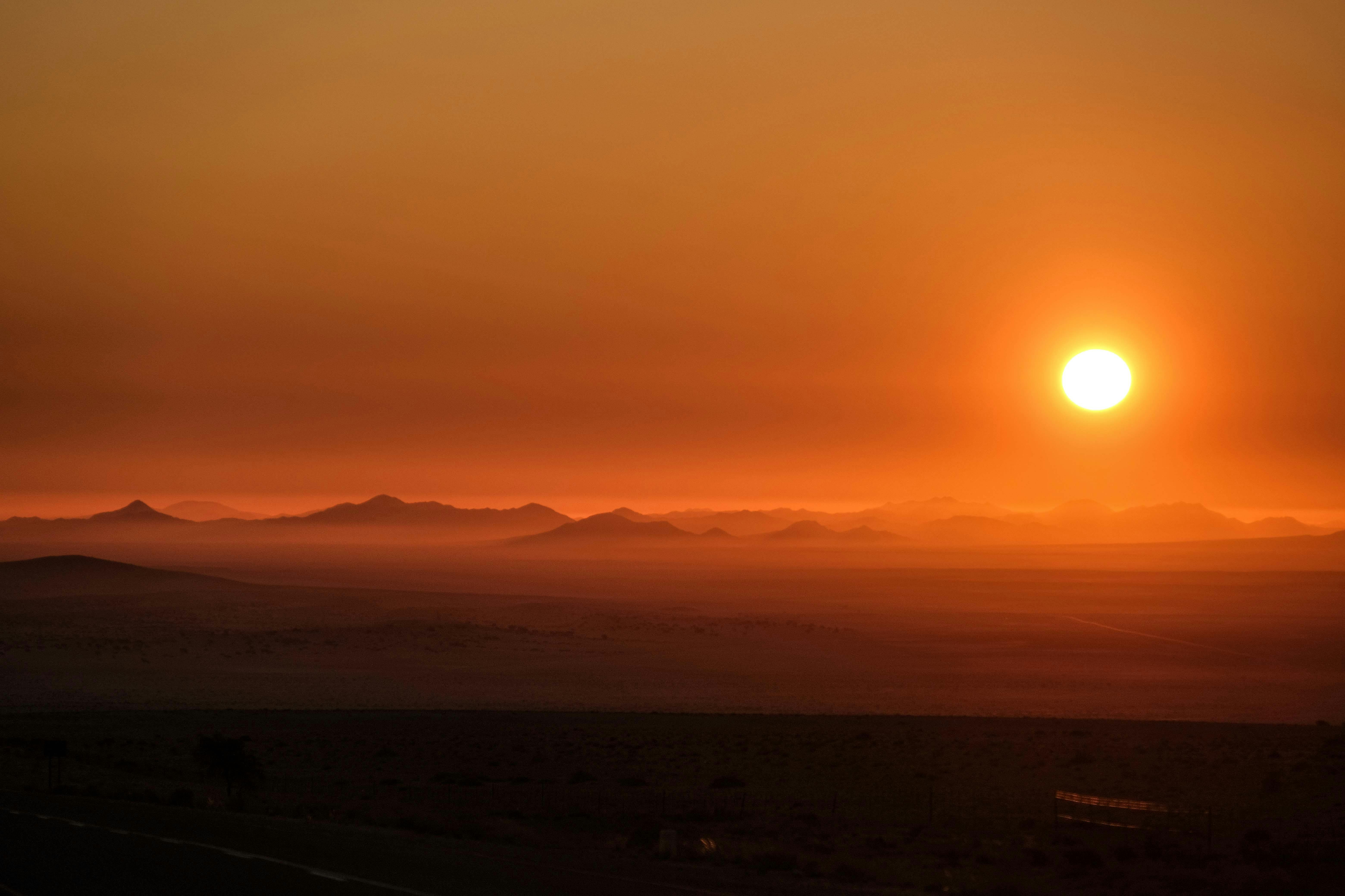 Stunning sunset casting vibrant orange hues over distant desert mountains