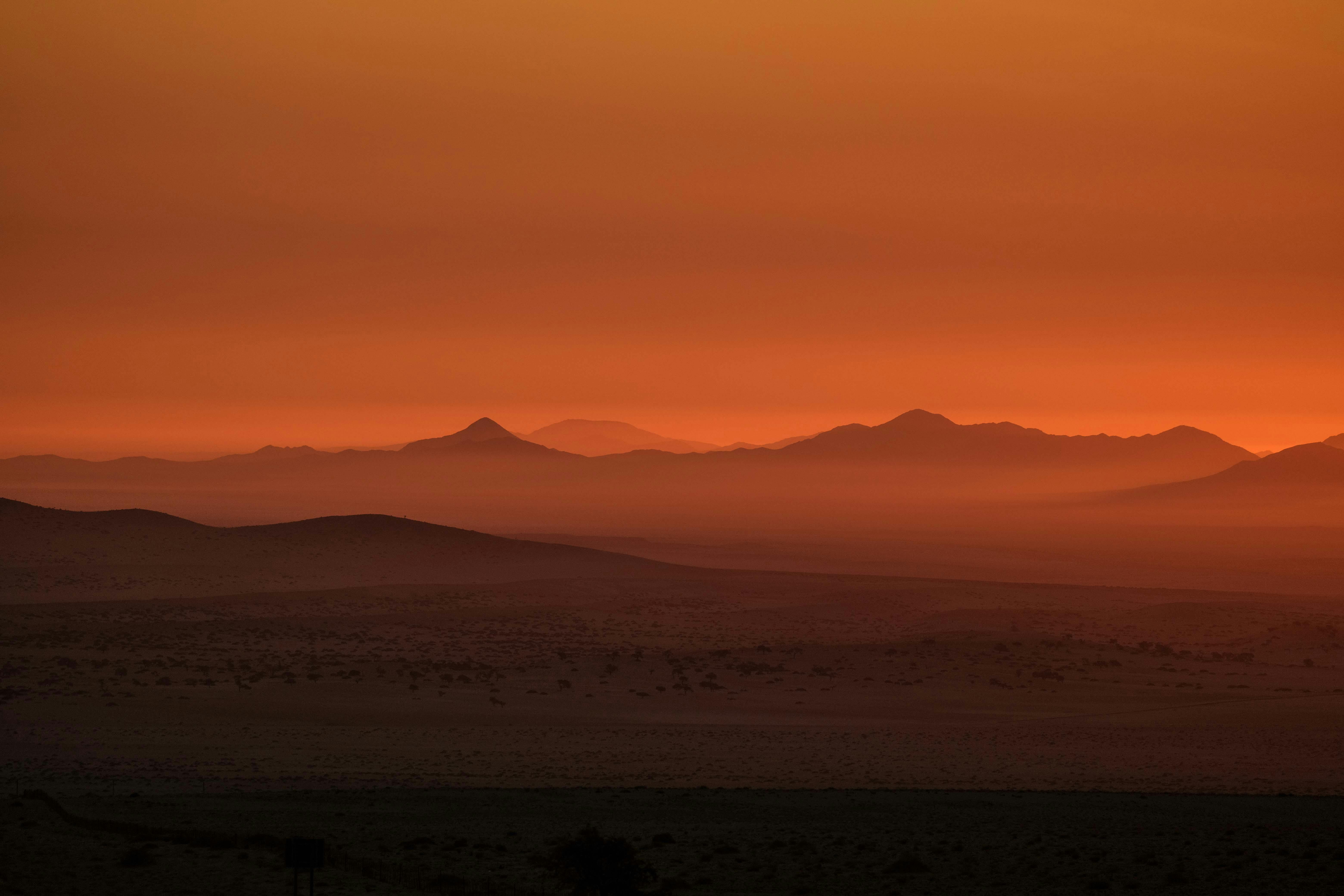 Beautiful desert landscape with mountain silhouettes and orange sunset sky